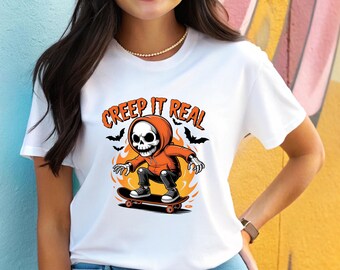 May include: White t-shirt featuring a cartoon skeleton in an orange hoodie skateboarding. The design includes the text "CREEP IT REAL" in orange, with black bats and flames. The skeleton is on a skateboard with red wheels.
