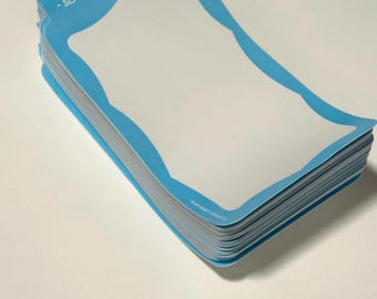 Op de afbeelding: Een stapel rechthoekige stickers met afgeronde, geschulpte randen en een lichtblauwe rand rondom een wit midden. De tekst SLAP ADDICT STICKER CO. is in het wit gedrukt op de bovenste blauwe rand van elke sticker in de stapel.