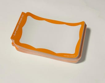 May include: A stack of rectangular stickers with rounded corners, featuring a white centre and a thick orange border. The text SLAP ADDICT STICKER CO is printed in white on the orange border along the left side and the bottom right corner.