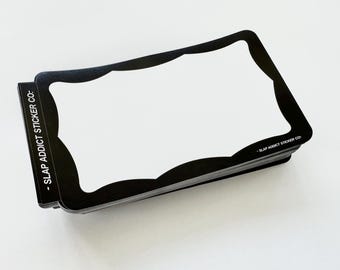 May include: A stack of rectangular stickers with a black border and a white centre. The black border features a scalloped inner edge. The text SLAP ADDICT STICKER CO. is printed in white on the left side and in the bottom right corner.
