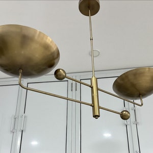 May include: A gold-toned modern chandelier with three circular light fixtures and three spherical accents.