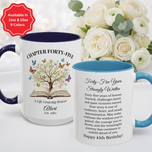 May include: White ceramic mug with a blue interior and handle, featuring the text "CHAPTER FORTY-FIVE" and "Forty-Five Years Strongly Written." The mug has a tree and butterfly design. Available in 11oz and 15oz, and 9 colors.