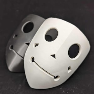 May include: Two 3D printed masks, one white and one gray, with simple facial features and cut-out eyes and mouth.