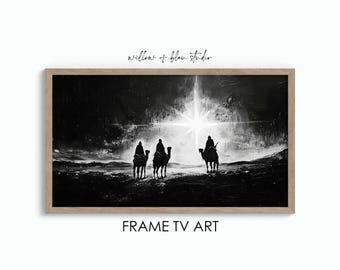 Op de afbeelding: Zwart-witte illustratie van drie figuren die op kamelen rijden naar een heldere ster aan de hemel. De afbeelding is ingelijst in een licht houten lijst. "willow + bleu studio" staat in de rechterbovenhoek van de afbeelding. "FRAME TV ART" staat onder de afbeelding.