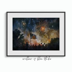 Puede incluir: Una pintura de acuarela de una multitud de personas silueteada contra un cielo oscuro con fuegos artificiales explotando por encima. Una bandera estadounidense ondea al viento a la izquierda de la multitud. La pintura est&aacute; titulada "willow + bleu studio".