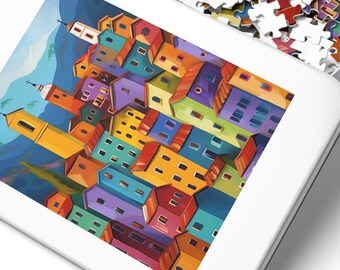Könnte beinhalten: Eine weiße Metall-Puzzledose mit offenem Deckel, die ein farbenfrohes Puzzle zeigt. Der Deckel zeigt ein fertiges Puzzlebild einer lebendigen Stadtlandschaft mit bunten Gebäuden und einem Bergpanorama. Puzzleteile sind verstreut.
