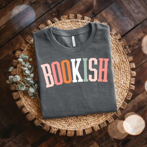 Camiseta unisex de jersey con fuente universitaria colorida y temática de libros: ideal para amantes de los libros, regalo para amantes de la biblioteca, regalos de lectura y eventos literarios.
