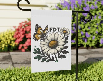 May include: A white garden flag with a black and orange butterfly, a white daisy with a yellow center, and the text "FDT" in black.