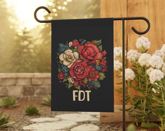 May include: A black garden flag with a floral design featuring red, white, and blue flowers. The text "FDT" is printed in white at the bottom of the flag.