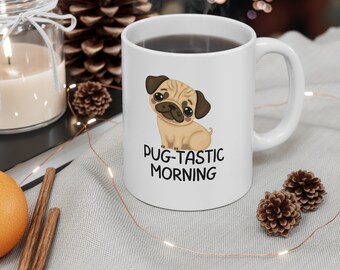 Könnte beinhalten: Weiße Keramik-Kaffeetasse mit einer Cartoon-Mops-Illustration und dem Text "Pug-tastic Morning".