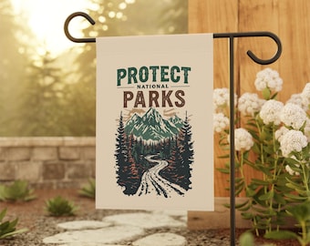 May include: A beige garden flag displaying the text "PROTECT NATIONAL PARKS" in green and brown. The flag features a graphic of a mountain range, a winding road, and evergreen trees. The flag is displayed on a black metal garden stake.