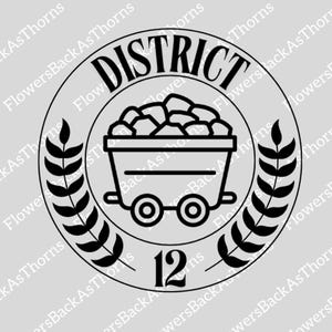May include: Black and white illustration of a coal mining cart with a pile of coal inside. The cart is on wheels and has a black and white wreath around it. The text "DISTRICT 12" is written in black on a white background.