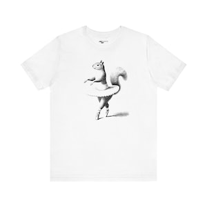 May include: A white t-shirt featuring a black and white illustration of a squirrel wearing a tutu and dancing.