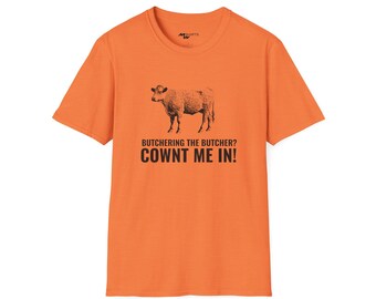 May include: Orange short-sleeved t-shirt with a black and white illustration of a cow and the text "Butchering the butcher? Cownt me in!"