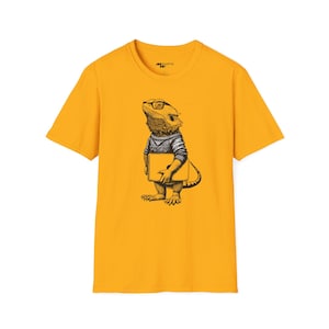 Peut inclure: Un t-shirt jaune avec une illustration en noir et blanc d'un dragon barbu portant des lunettes et tenant un livre. Le texte "Moments" est imprimé sur le t-shirt.