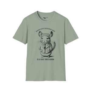 May include: A light green t-shirt featuring a black and white illustration of a chinchilla wearing a suit and tie. The text "Behind every successful boss is a very tired admin" is printed on the shirt.