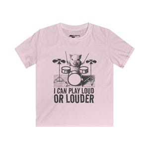 May include: Pink youth t-shirt with a black and white illustration of a pig playing drums. The text "I can play loud or louder" is printed below the illustration.
