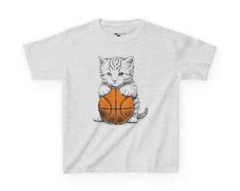 May include: A light gray t-shirt featuring a detailed illustration of a kitten holding a basketball. The kitten is in black and white, while the basketball is orange. The shirt has a crew neck and short sleeves.
