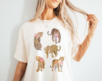 May include: A white t-shirt with a graphic print of five leopards wearing pink bows. The text "IVORY" is printed in the bottom right corner of the image.