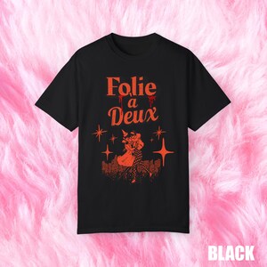 May include: Black t-shirt with a red graphic print of a couple dancing. The text "Folie a Deux" is printed in red above the couple.