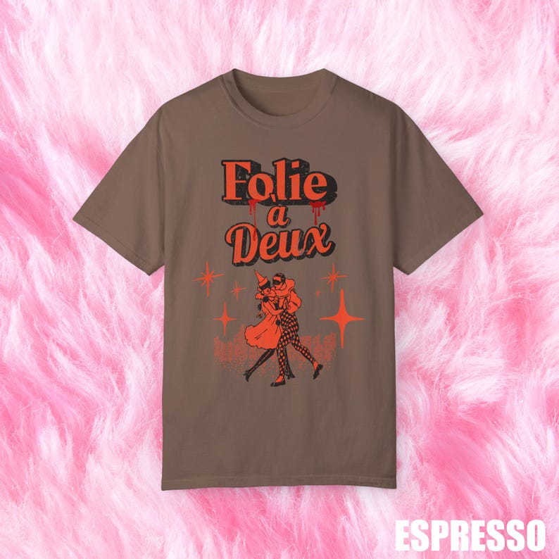 May include: A brown t-shirt with the text "Folie a Deux" in red and a vintage illustration of a couple dancing.