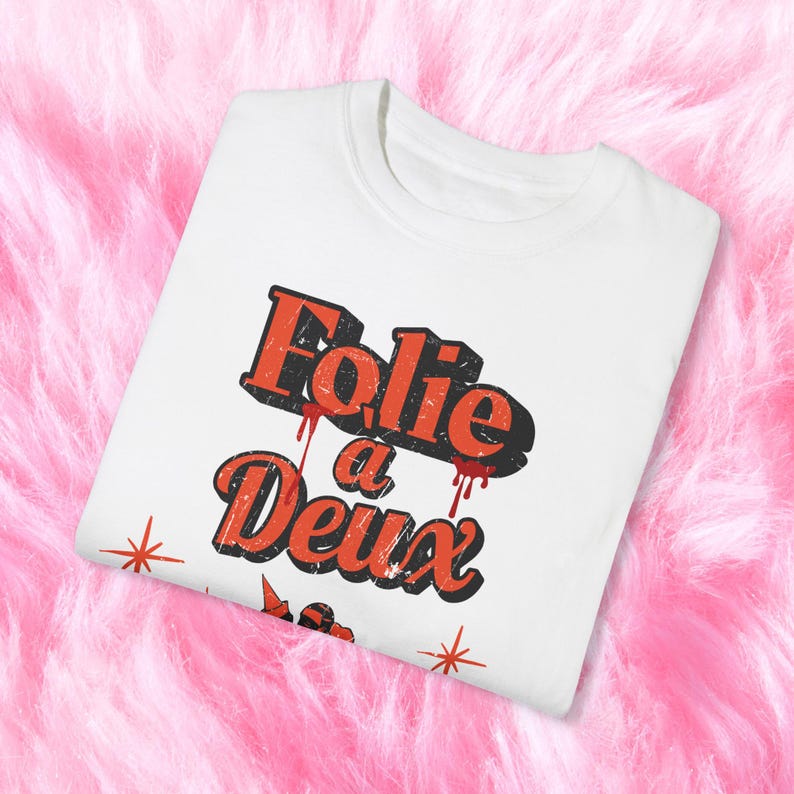 May include: White t-shirt with a red and black graphic that says "Folie a Deux" with red paint splatters.