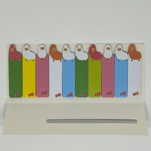Op de afbeelding: Een set van 10 kleurrijke sticky notes met een cartoon lama-ontwerp. Elke notitie heeft een andere kleur en een lama met een andere uitdrukking.