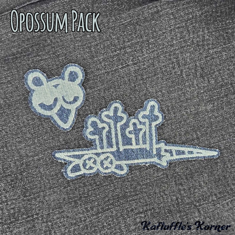 May include: Two embroidered patches on a dark grey denim fabric. One patch depicts a stylised opossum head, and the other shows a long, pointed shape with four vertical tree-like structures. The text OPOSSUM PACK and Kafluffle's Korner are visible.