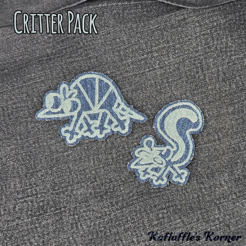 May include: Two denim fabric patches featuring embroidered outlines of an armadillo and a skunk. The text CRITTER PACK is printed at the top, and Kafluffle's Korner is printed at the bottom. The patches are displayed on a dark grey denim background.