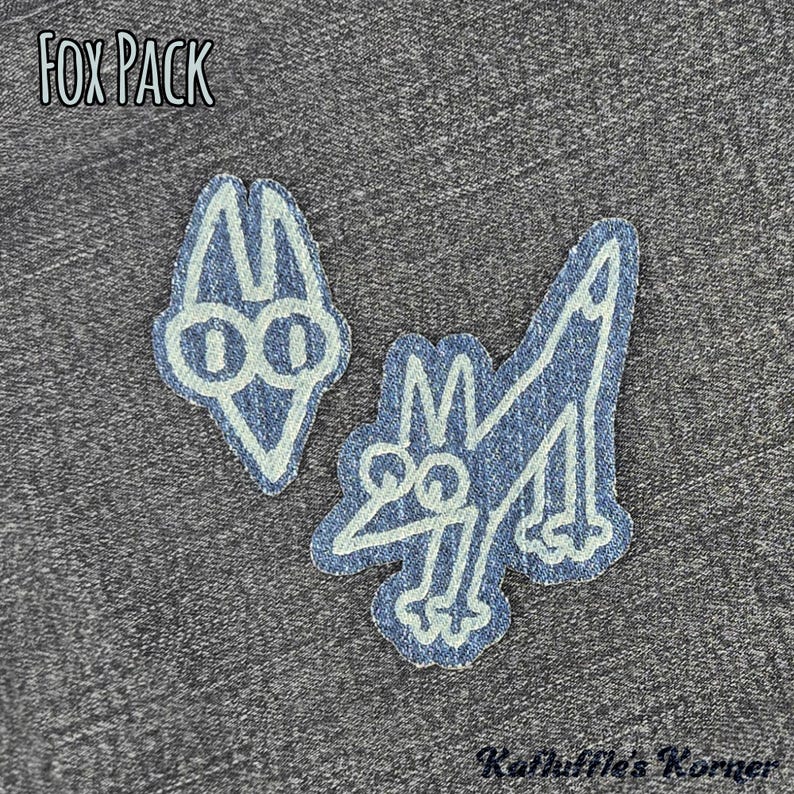 May include: Two denim fabric patches featuring white embroidered outlines of a fox head and a full-body fox. The text FOX PACK is printed in the upper left corner, and the text Kathuffle's Korner is printed in the lower right corner.