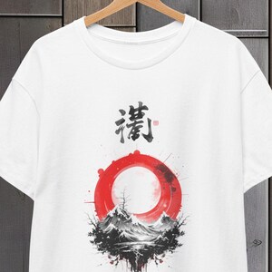 Puede incluir: Camiseta blanca con un diseño de inspiración japonesa en negro y rojo. El diseño presenta un círculo rojo con una escena de montaña en su interior y la palabra japonesa "清" encima.