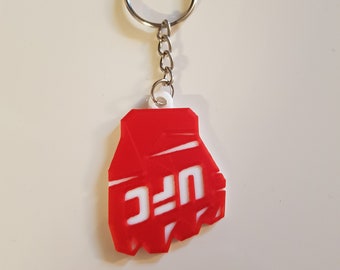 May include: Red and white keychain shaped like a fist with the word "UFC" in white letters.
