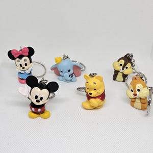 Peut inclure: Un ensemble de six porte-clés de personnages Disney colorés. Les personnages incluent Mickey Mouse, Minnie Mouse, Dumbo, Winnie l'ourson et deux écureuils.