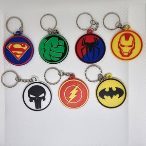 Può includere: Sette portachiavi di supereroi diversi con anelli di metallo. I portachiavi sono rotondi e presentano diversi loghi di supereroi, tra cui Superman, Hulk, Spiderman, Iron Man, Punisher, Flash e Batman. I portachiavi sono tutti realizzati in un materiale simile alla gomma e sono colorati.
