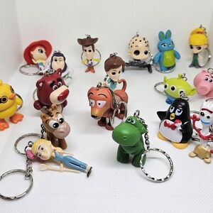 Peut inclure: Un ensemble de 15 porte-clés colorés représentant des personnages de Toy Story. Les personnages incluent Woody, Buzz l'Éclair, Jessie, Rex,  Hamm,  Slinky Dog,  Bullseye,  M. Patate,  Bergère,  Fourchette, et plus encore.