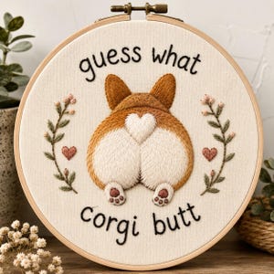 Puede incluir: Un bastidor de bordado circular que contiene un panel de tela con una ilustración bordada de la parte trasera de un corgi marrón y blanco. El texto "guess what" está arriba y "corgi butt" abajo, flanqueado por dos ramas florales y corazones.
