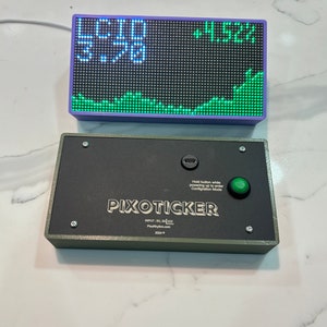 May include: A digital stock ticker with a purple frame displays numbers and a green line graph. Below it, a black box with the text "PIXOTICKER" and a green button is visible. The text "Hold button while powering up to enter Configuration Mode" is also present.