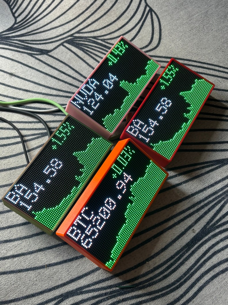 May include: Four rectangular LED displays showing stock market data. Each display has a different colored frame: pink, red, orange, and green. The displays show stock tickers, prices, and percentage changes in white and green.