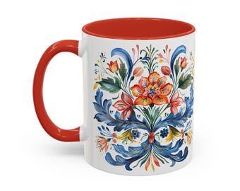 Könnte beinhalten: Weiße Keramiktasse mit rotem Rand und einem floralen Design in Blau, Grün, Orange und Gelb. Das Design zeigt eine große orangefarbene Blume mit blauen und grünen Blättern.