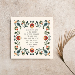 May include: A white card with a colorful floral border and a traditional Scandinavian prayer in black text. The prayer reads: "In Jesus' name we go to the table and eat and drink of your word. You, God, to honor, us for good, so we get food in Jesus' name, Amen."