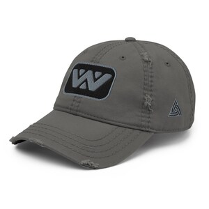 May include: Distressed grey baseball cap with a black and grey "W" patch on the front. The cap has a curved peak and a small triangular logo on the side. The fabric has a worn, vintage appearance.