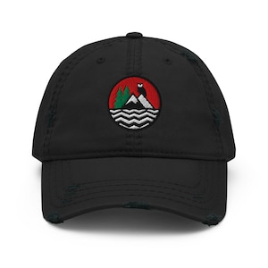 May include: Black distressed baseball cap with an embroidered circular patch. The patch shows a mountain scene with trees, a bear, and water waves, set against a red background. The cap has a curved peak and a worn, vintage appearance.