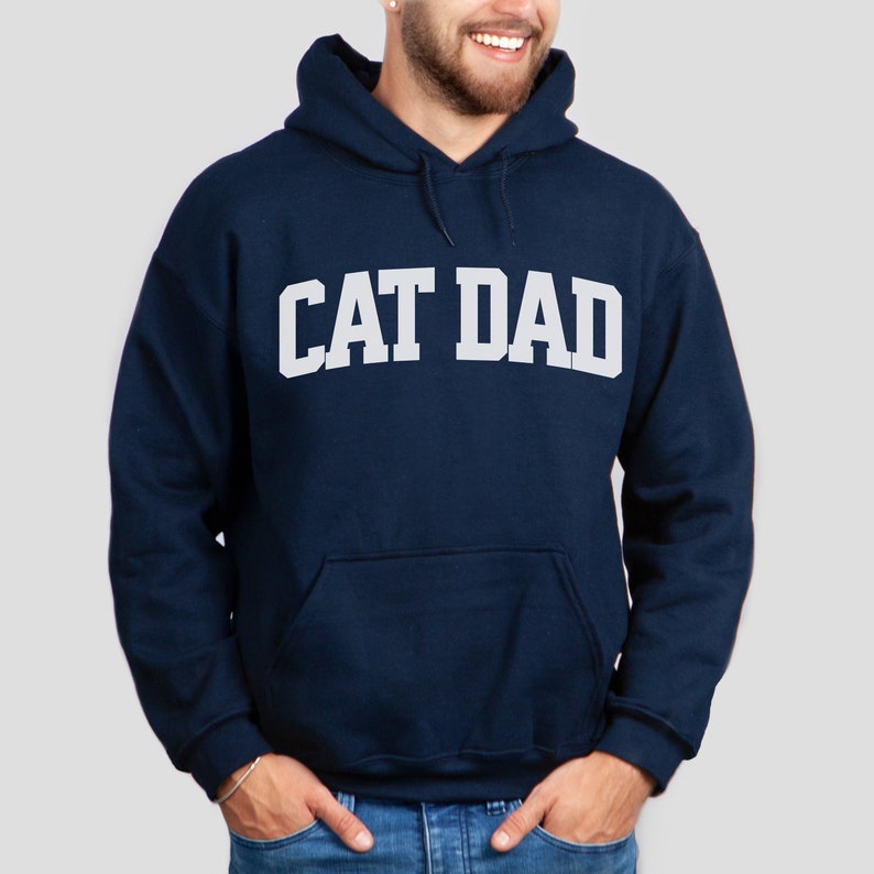 Navy colored pullover hoodie with Cat Dad printed in an arch on the front in white.  Varsity athletic block style font printed on the hooded sweatshirt.