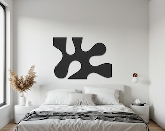 Könnte beinhalten: Ein großes, abstraktes schwarzes Wandkunstwerk mit organischer Form hängt über einem Bett. Das Schlafzimmer hat eine neutrale Farbpalette mit weißen Wänden, Bettwäsche und Nachttischen. Getrocknetes Ziergras steht in einer weißen Vase.
