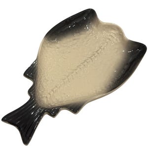 Könnte beinhalten: Eine keramische Servierschale in Fischform. Die Schale ist überwiegend cremefarben mit einem Farbverlauf von Schwarz an den Rändern, Flossen und Schwanz. Das Innere hat ein strukturiertes Muster, das an Fischgräten erinnert.