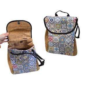 Pode incluir: Uma mochila de cortiça e tecido estampado com fecho de aba e correias ajustáveis. O tecido apresenta um design de patchwork colorido de formas e padrões geométricos.