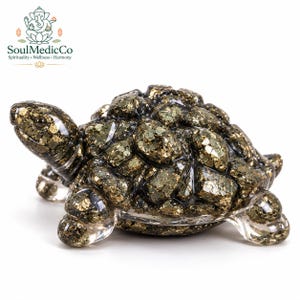 May include: A turtle figurine crafted from clear resin embedded with metallic gold and bronze pyrite mineral fragments. The sculpture features a detailed shell with segmented stone pieces and smooth, transparent limbs and head.