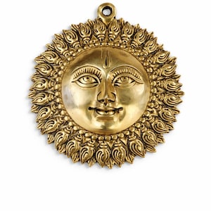 May include: A golden sun face wall hanging with detailed facial features and a radiant, ornate border. The sun has a serene expression and a loop for hanging. This decorative piece is likely made of metal.