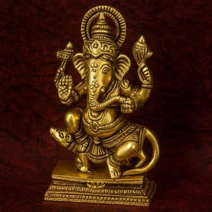 Op de afbeelding: Een goudkleurig beeld van de hindoe&iuml;stische god Ganesha, zittend op een rat. Het beeld heeft ingewikkelde details en staat op een rechthoekige basis. De tekst "Soul MedicCo" is onderaan zichtbaar.