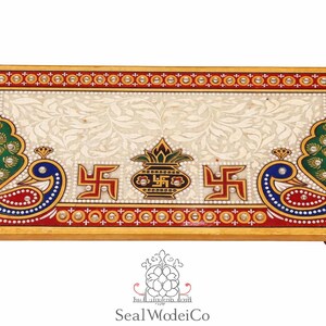 Pu&ograve; includere: Vassoio rettangolare decorativo in marmo con bordo dorato. Il vassoio presenta uno sfondo color crema con un motivo floreale, disegni di pavoni e simboli religiosi. Il vassoio &egrave; supportato da piccoli piedini in legno.
